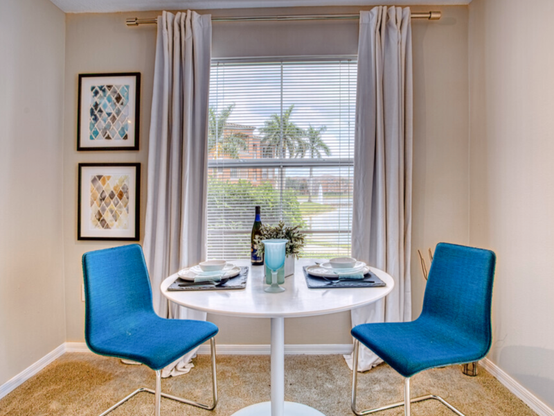 This image shows a unique small dining table near the window with an adorable painting on the wall.