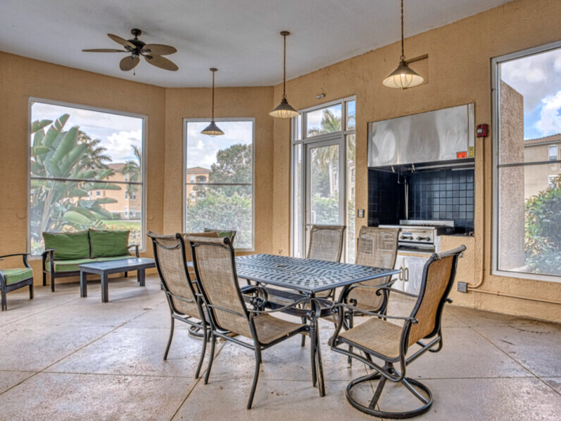 This image shows a screened-in outdoor kitchen and grill that is comfortable and relaxing.